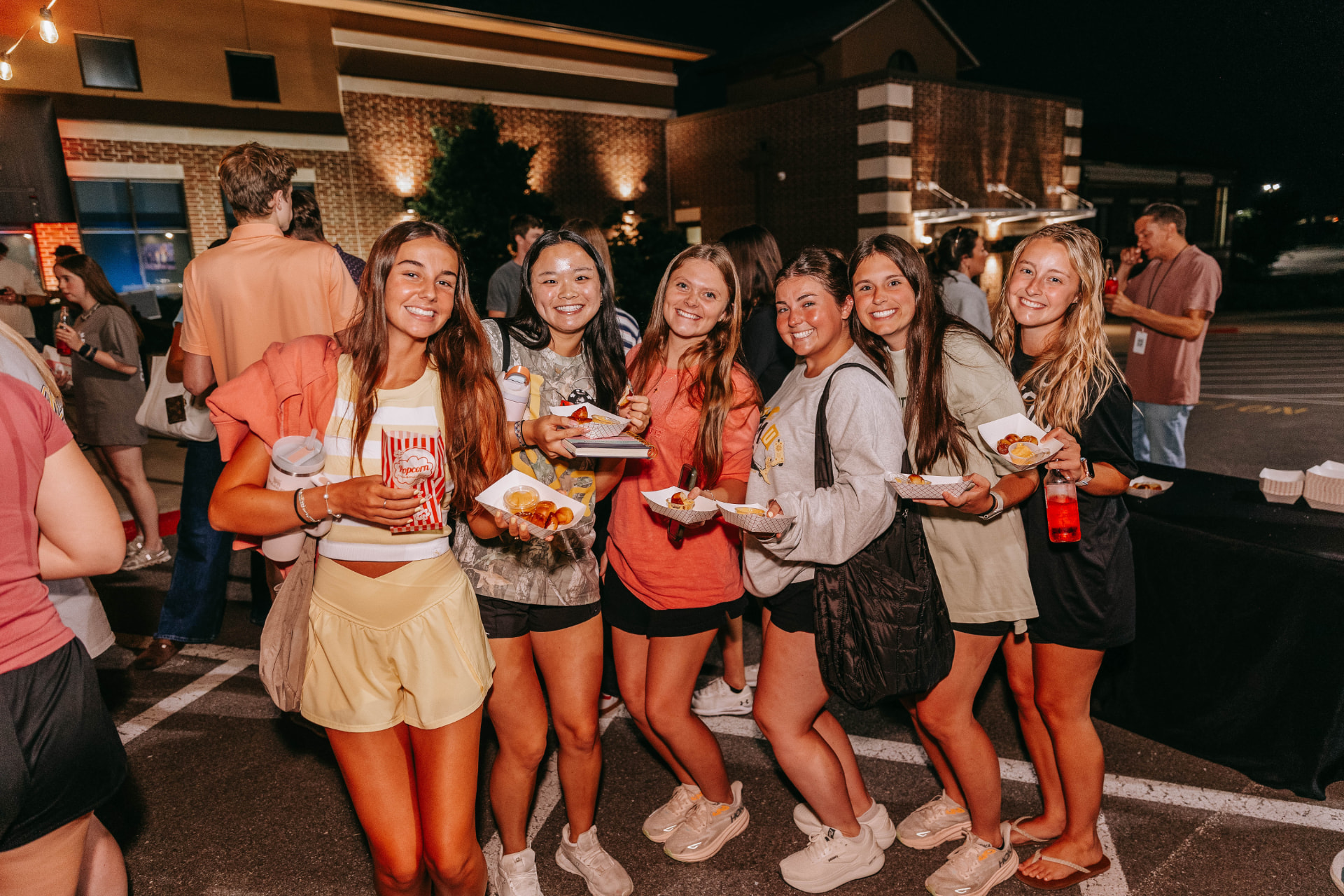 Guests holding trays of pretzel bites and cheese cups at a night event
